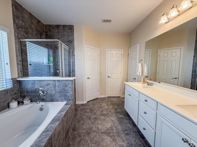 bathroom featuring visible vents, a garden tub, double vanity, a stall shower, and a sink