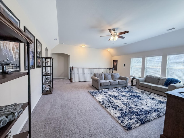 carpeted living room with lofted ceiling, a ceiling fan, arched walkways, and visible vents