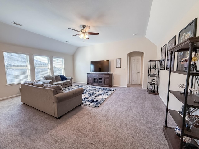 carpeted living area with baseboards, visible vents, arched walkways, ceiling fan, and vaulted ceiling