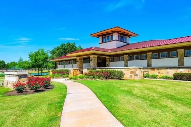 view of front facade with a standing seam roof, metal roof, and a front yard