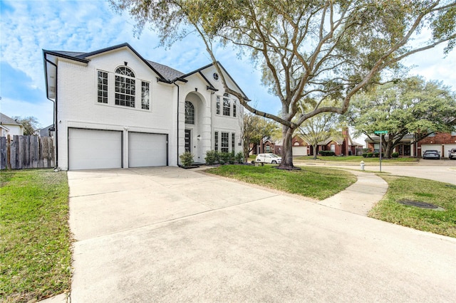 french country inspired facade featuring a front yard, an attached garage, driveway, and fence