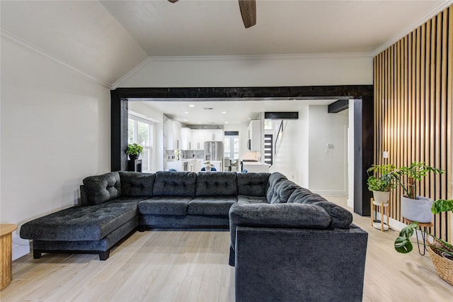 living room featuring a ceiling fan, lofted ceiling, stairs, light wood-style floors, and crown molding