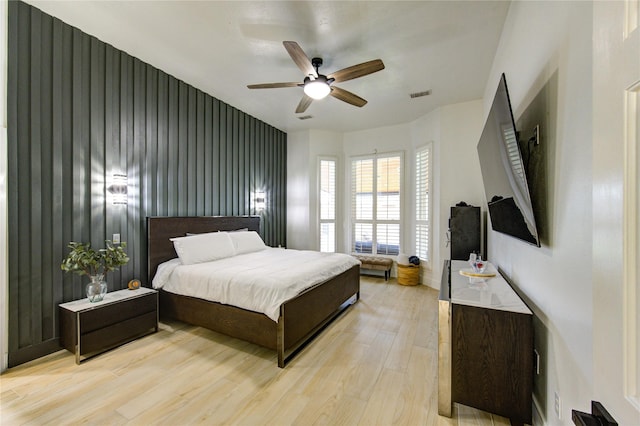 bedroom featuring light wood finished floors, visible vents, and a ceiling fan