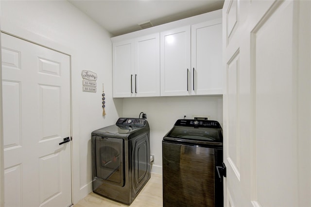 laundry room featuring visible vents, baseboards, light wood-style flooring, cabinet space, and separate washer and dryer