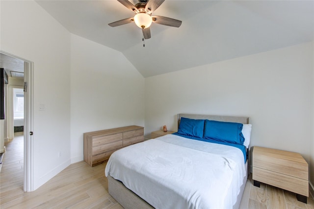 bedroom with baseboards, light wood-style flooring, a ceiling fan, and vaulted ceiling