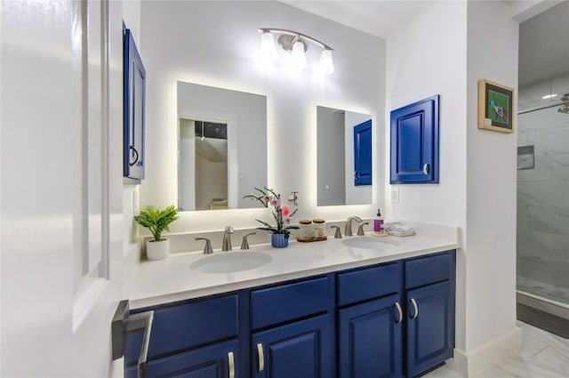 bathroom with a tile shower, marble finish floor, double vanity, and a sink