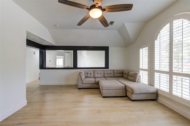 living area with visible vents, a ceiling fan, baseboards, light wood-style floors, and lofted ceiling