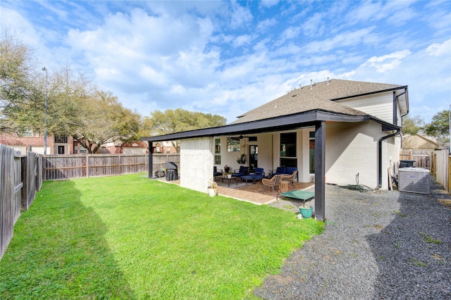 back of property with a lawn, a ceiling fan, a fenced backyard, brick siding, and a patio area