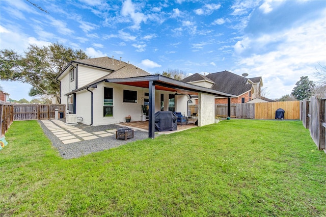 rear view of property featuring a patio area, a lawn, a fire pit, and a fenced backyard