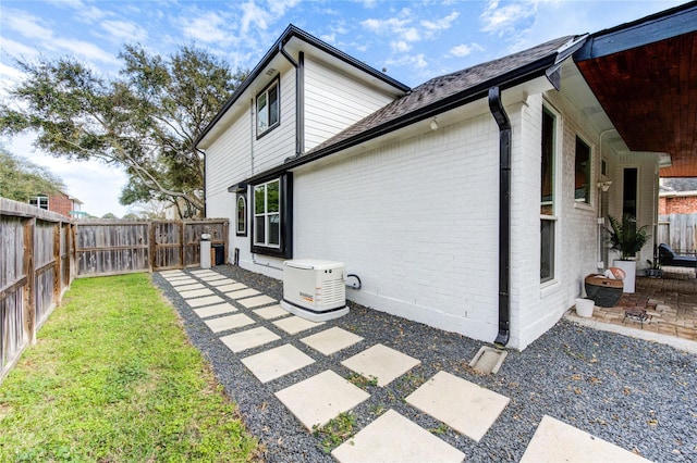 back of house featuring a yard, brick siding, a fenced backyard, and a patio area