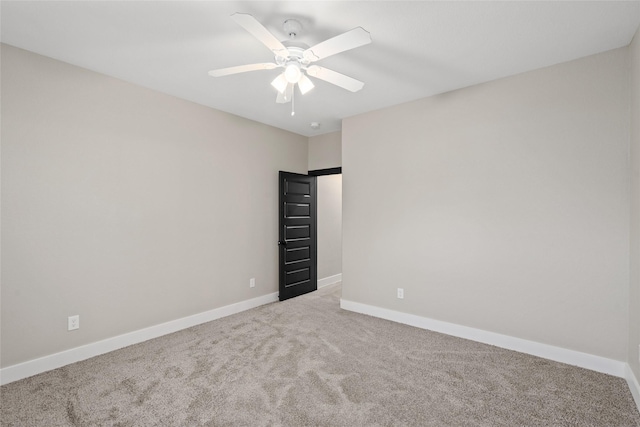 carpeted empty room featuring baseboards and a ceiling fan