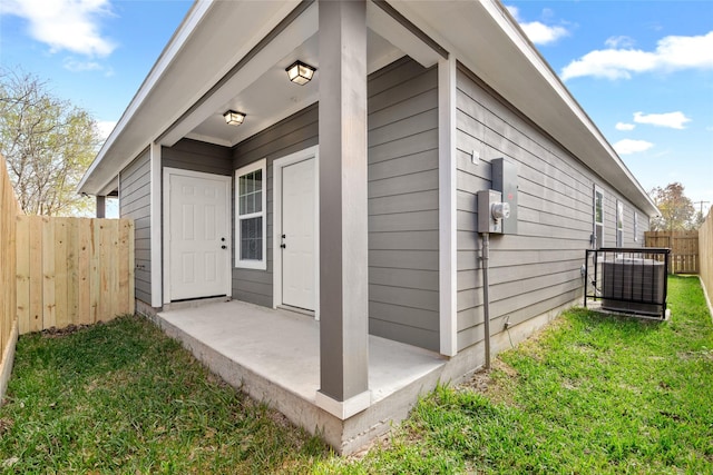 doorway to property featuring a patio area, a yard, and fence