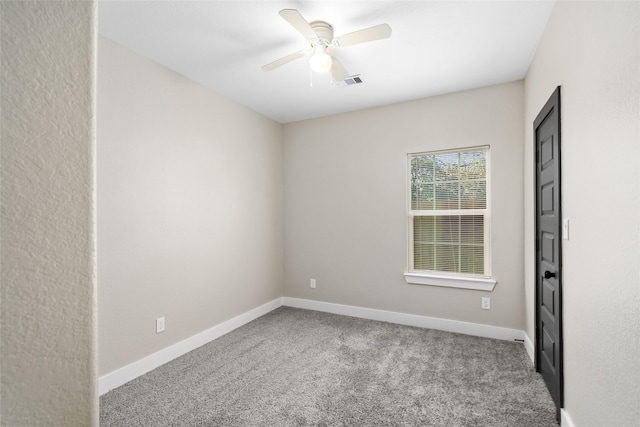 carpeted spare room with visible vents, baseboards, and ceiling fan