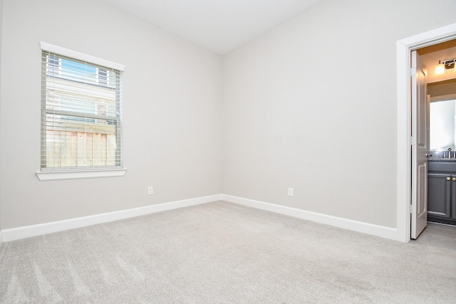 spare room featuring baseboards and light carpet