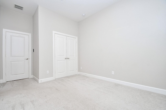 unfurnished bedroom with visible vents, baseboards, light colored carpet, and a closet