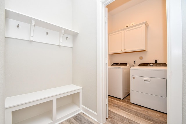 washroom featuring light wood-style flooring, cabinet space, and washer and clothes dryer