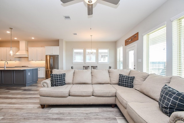 living area with recessed lighting, visible vents, ceiling fan with notable chandelier, and light wood-style floors