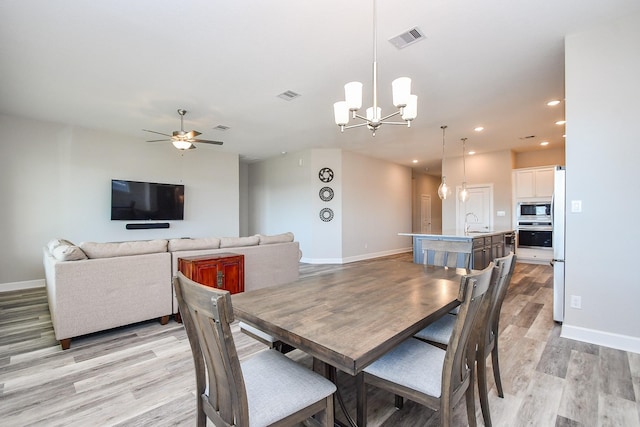 dining space with ceiling fan with notable chandelier, recessed lighting, visible vents, and light wood finished floors