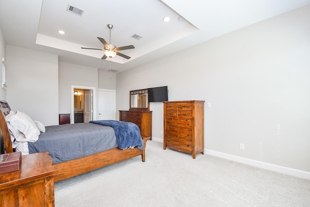 bedroom with light carpet, visible vents, baseboards, and a tray ceiling