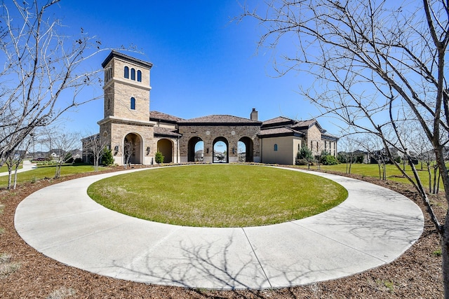 exterior space featuring a chimney, curved driveway, a front lawn, stone siding, and brick siding