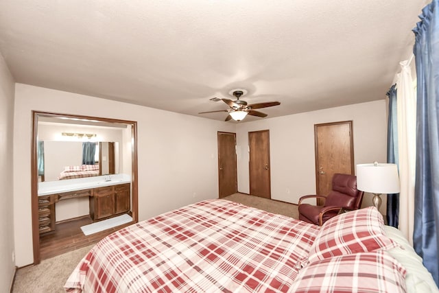 carpeted bedroom featuring connected bathroom, a ceiling fan, two closets, and a textured ceiling