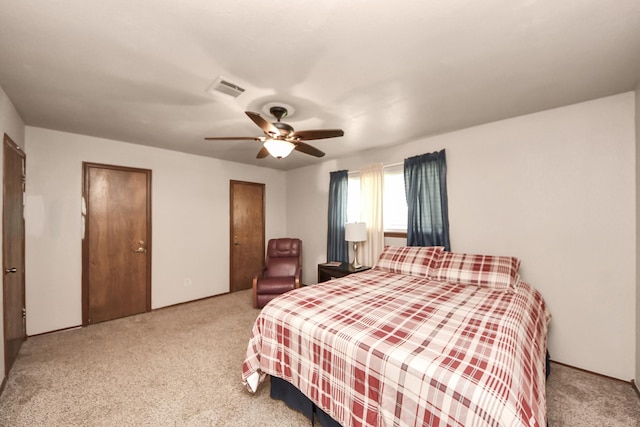 bedroom with carpet flooring, visible vents, two closets, and ceiling fan