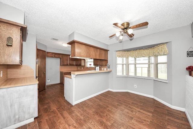 kitchen featuring visible vents, a ceiling fan, a peninsula, light countertops, and dark wood-style flooring