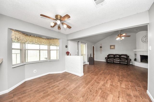 unfurnished living room featuring visible vents, wood finished floors, a ceiling fan, and vaulted ceiling