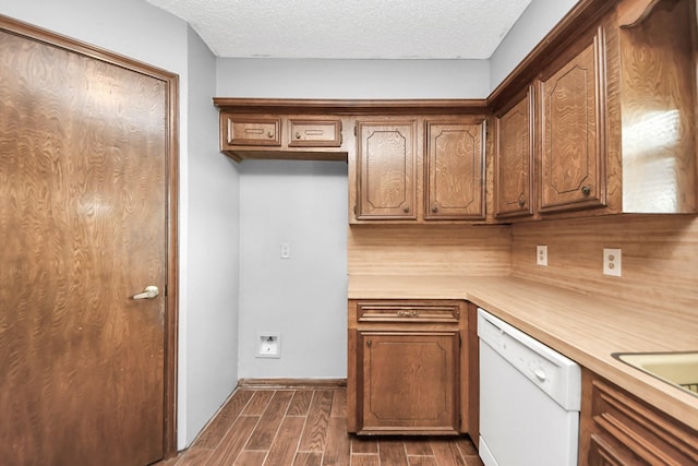 kitchen featuring wood finish floors, a textured ceiling, brown cabinetry, white dishwasher, and light countertops