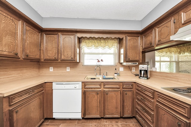 kitchen featuring a textured ceiling, light countertops, white dishwasher, and a sink