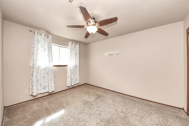 carpeted spare room featuring visible vents, baseboards, and a ceiling fan