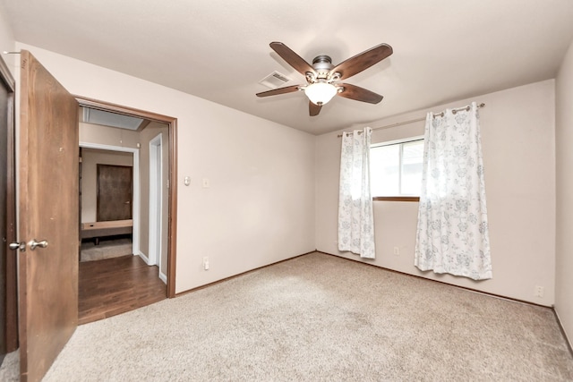 spare room featuring visible vents, baseboards, attic access, carpet flooring, and a ceiling fan