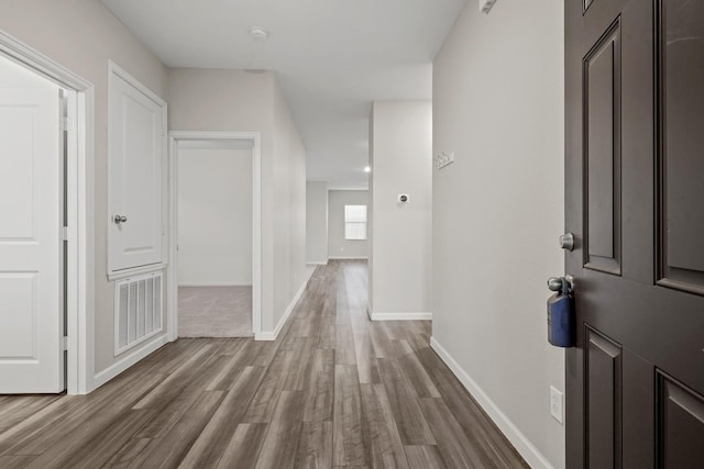 corridor with visible vents, baseboards, and wood finished floors