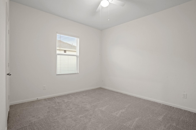 carpeted spare room featuring baseboards and ceiling fan