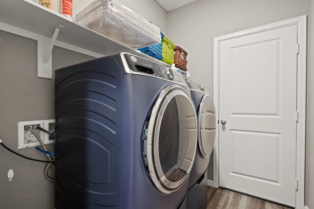 washroom featuring independent washer and dryer, wood finished floors, and laundry area