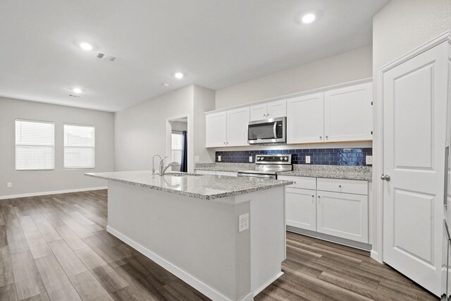 kitchen featuring a sink, backsplash, dark wood-type flooring, stainless steel appliances, and a kitchen island with sink