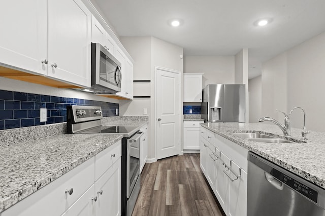 kitchen with a sink, decorative backsplash, white cabinets, stainless steel appliances, and dark wood-style flooring