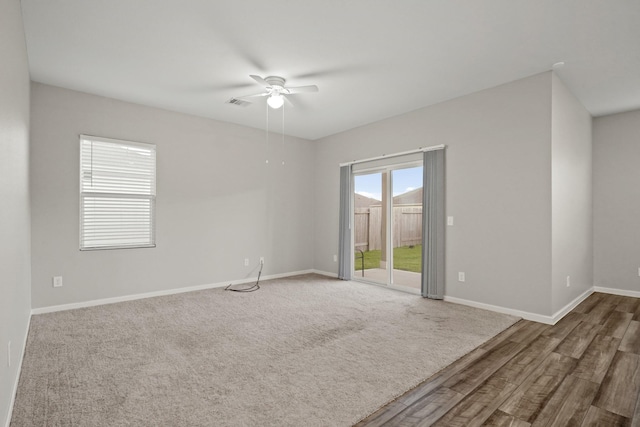 unfurnished room with carpet, visible vents, a ceiling fan, and baseboards