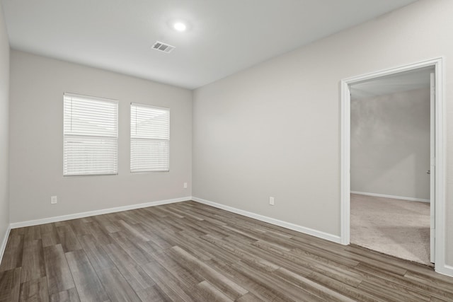 unfurnished room featuring visible vents, baseboards, and wood finished floors