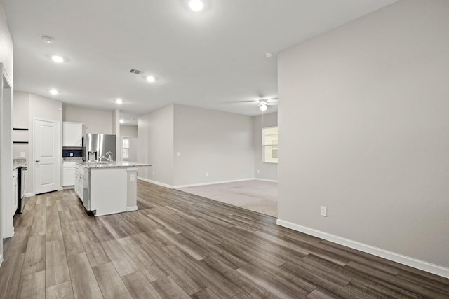 kitchen featuring an island with sink, wood finished floors, open floor plan, white cabinetry, and stainless steel fridge with ice dispenser