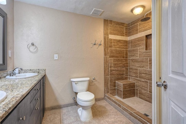 bathroom with visible vents, toilet, double vanity, a tile shower, and a sink