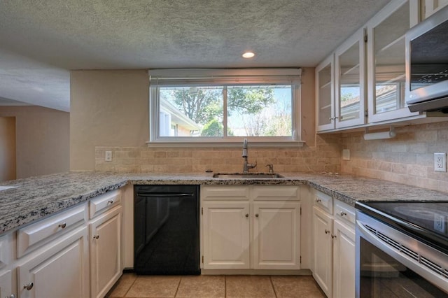 kitchen with a sink, white cabinets, glass insert cabinets, appliances with stainless steel finishes, and tasteful backsplash