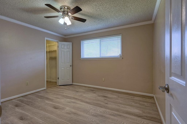 unfurnished bedroom with baseboards, a textured ceiling, wood finished floors, and ornamental molding