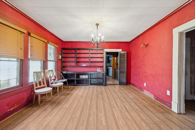 living area with baseboards, an inviting chandelier, wood finished floors, and ornamental molding