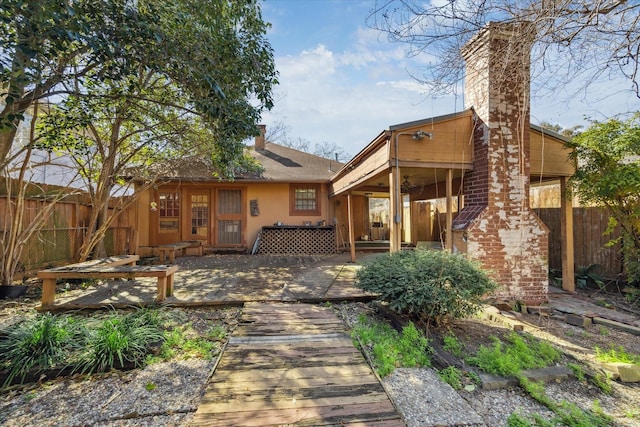 rear view of property with a patio, a chimney, and fence