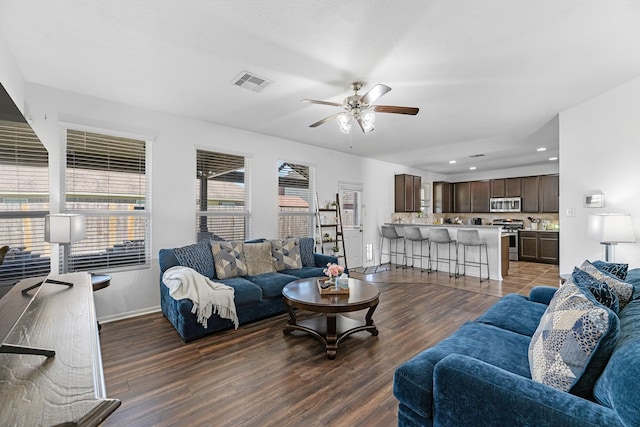 living area featuring visible vents, baseboards, ceiling fan, and wood finished floors