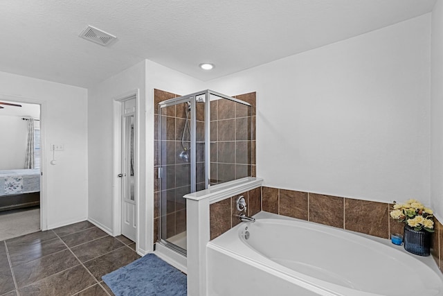 ensuite bathroom featuring visible vents, a stall shower, a textured ceiling, a bath, and connected bathroom