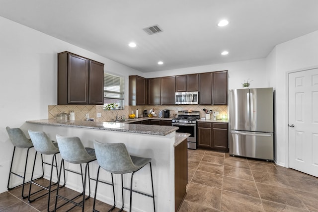 kitchen with visible vents, dark brown cabinets, a peninsula, and stainless steel appliances