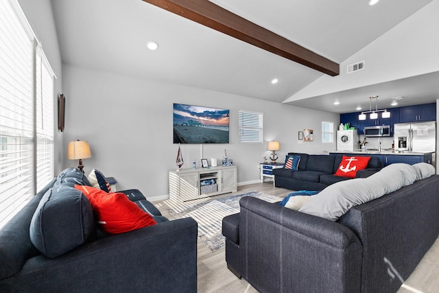 living room with vaulted ceiling with beams, visible vents, a wealth of natural light, and light wood-type flooring