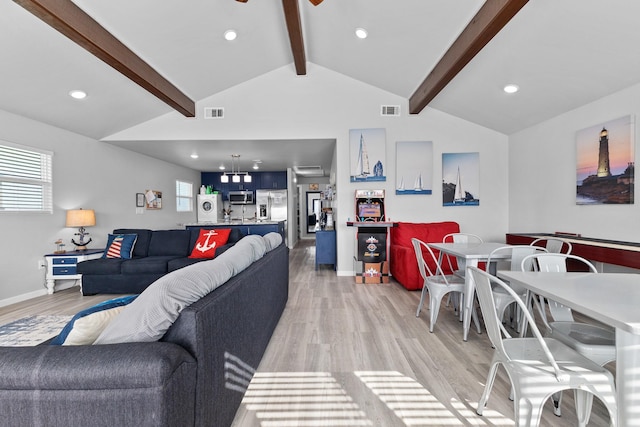 living area featuring light wood-type flooring, visible vents, ceiling fan, and vaulted ceiling with beams